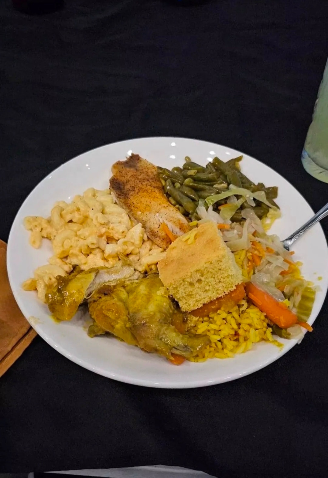Soul food plate with mac and cheese, curry chicken, fried fish, yellow rice, and cornbread